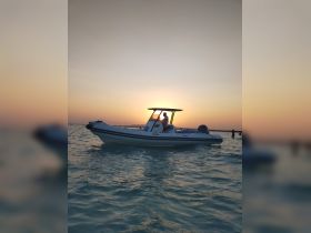 A scenic sunset view featuring a boat with a person onboard, creating a perfect backdrop for a tranquil evening on the water.