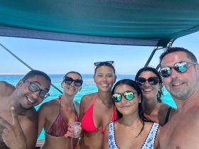 A joyful group of friends enjoys a sunny day on the water, capturing memories with drinks in hand — perfect for summer celebrations and fun on a boat.