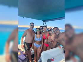 A joyful group of friends enjoys a sunny day on the water, capturing memories aboard a boat — perfect for summer adventures and celebrations.