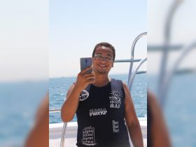 A smiling individual takes a selfie on a boat, capturing a moment of joy on the water. Perfect for showcasing fun experiences during a boating adventure.