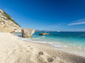 A picturesque beach scene featuring clear turquoise waters and rocky cliffs, perfect for a relaxing day by the sea.