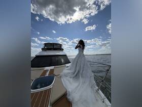 A stunning bride poses on the deck of a boat, showcasing her elegant wedding dress against a picturesque sky — a perfect moment for a nautical wedding celebration.