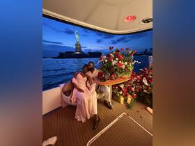 A romantic couple enjoys a special moment aboard a boat with the Statue of Liberty in the background, surrounded by beautiful flowers — perfect for unforgettable celebrations.