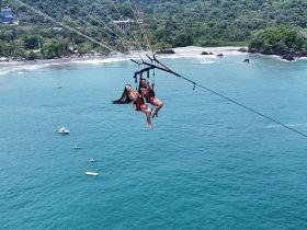 A thrilling parasailing adventure over the turquoise ocean, showcasing a couple enjoying breathtaking views and the excitement of soaring high above the coastline.