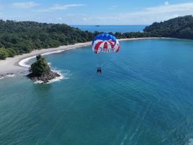 A thrilling parasailing adventure over a stunning beach, showcasing the beautiful coastline and clear turquoise waters — perfect for adventure seekers.
