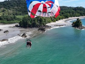 A thrilling parasailing adventure over a stunning beach, capturing a group enjoying the breathtaking views of the coastline and turquoise waters.