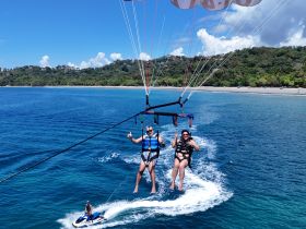 A thrilling parasailing experience over crystal-clear waters, showcasing a couple enjoying an adventurous day on the ocean.