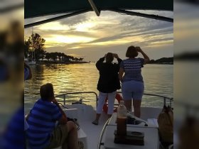 A group of friends captures the stunning sunset from the deck of a boat, creating a memorable moment on the water.