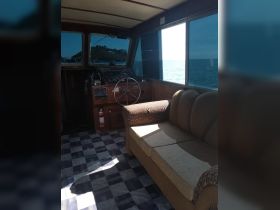 The interior of a boat's helm area featuring a comfortable seating arrangement and navigational controls, perfect for a relaxing day on the water.