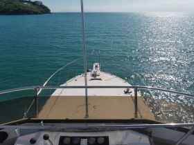 A stunning view from the front of a yacht cruising through clear turquoise waters, showcasing the vessel's sleek design and the serene ocean backdrop.