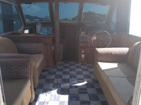 Interior view of a boat's cabin featuring comfortable seating and a helm, perfect for relaxing while navigating the waters.