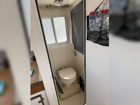 Interior view of a boat's bathroom, featuring a compact toilet and storage area, showcasing the practical amenities available on board.