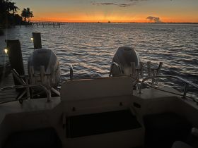 A serene sunset view from the back of a boat, showcasing the tranquil waters and dock, perfect for evening cruises.