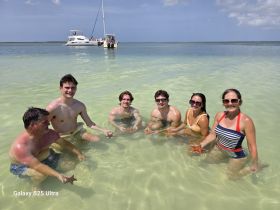 A lively group of friends enjoys a fun day at the beach, interacting with starfish in shallow waters — a perfect snapshot of aquatic adventure.