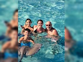 A joyful group of children and an adult interact with stingrays in shallow waters, creating unforgettable memories during their aquatic adventure.