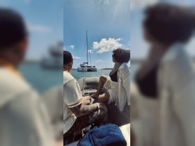 A couple enjoys a scenic boat ride, gazing at a sailboat in the distance — a perfect moment for relaxation and adventure on the water.