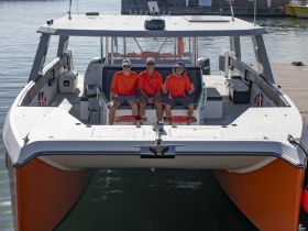 Three crew members pose cheerfully on the deck of a boat, ready for an exciting day on the water. Perfect for showcasing the friendly atmosphere of boating adventures.