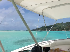 A scenic view from the helm of a boat, showcasing the stunning turquoise waters and lush greenery in the background — perfect for a day of exploration on the water.