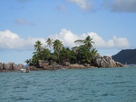 A picturesque view of an island with lush palm trees and rocky formations, featuring boats nearby, perfect for exploring tropical destinations.