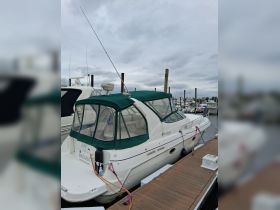 A well-maintained cruiser yacht docked at the marina, showcasing its sleek design and green canopy.