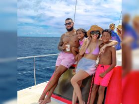 A joyful family enjoys their time aboard a boat, capturing fun moments together against a beautiful ocean backdrop.