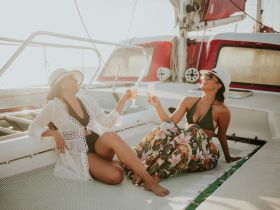 Two friends enjoy cocktails on the deck of a yacht, basking in the sun — a perfect moment for relaxation and celebration on the water.
