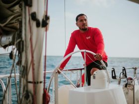 A skilled sailor navigates the helm of a sailboat, showcasing the beauty of sailing on open waters.