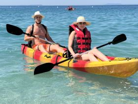 A couple enjoys kayaking in clear waters, showcasing a fun and adventurous day on the water.
