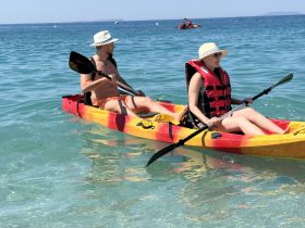 A couple enjoys kayaking in crystal-clear waters, showcasing the perfect summer adventure on the water.