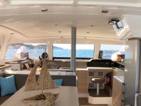 Interior view of a modern boat cabin featuring a helm and comfortable seating, perfect for relaxing while enjoying the scenic ocean views.