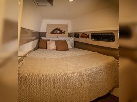 Cozy cabin interior featuring a comfortable bed and decorative marine-themed accents, perfect for relaxing on a boat getaway.