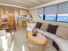 A cozy interior view of a yacht's cabin featuring comfortable seating and a dining area, perfect for relaxing while enjoying the ocean views.
