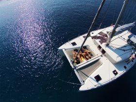 A lively group enjoys sunbathing on the deck of a catamaran, making the most of their day on the water — perfect for summer parties and relaxation.