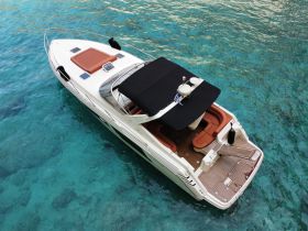 A stunning aerial view of a sleek speedboat gliding through crystal-clear waters, showcasing its elegant design and spacious deck — perfect for luxury outings on the water.