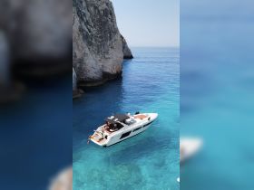 A group enjoys a sunny day on a boat in crystal-clear turquoise waters, perfect for swimming and relaxation near stunning cliffs.