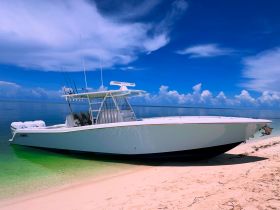 A sleek speedboat rests on a sandy beach under a vibrant blue sky, showcasing its modern design and perfect for thrilling water adventures.