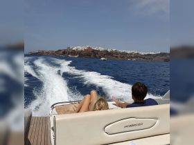 A couple relaxes on the deck of a boat, enjoying stunning views of the island coastline — a perfect moment for a romantic cruise.