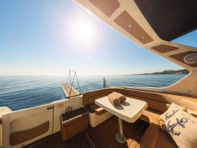 A serene view of the interior seating area on a boat, featuring a table and decorative pillows, perfect for relaxing while enjoying the calm waters.
