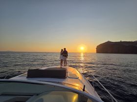 A couple enjoys a romantic moment on the bow of a yacht, watching the sunset over the horizon — an idyllic setting for special celebrations or intimate getaways.