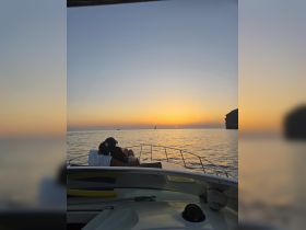 A couple enjoys a romantic sunset on the deck of a yacht, creating the perfect atmosphere for memorable moments on the water.
