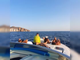 A group of friends relaxes on the bow of a boat, enjoying the ocean view and the warm sun — a perfect moment for leisure and camaraderie on the water.