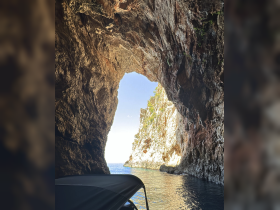 A stunning view from inside a cave, showcasing the beautiful coastline and clear waters beyond — perfect for exploring hidden gems on a boating adventure.