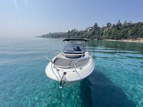 A sleek speedboat anchored in crystal-clear waters, surrounded by a picturesque coastline — perfect for exploring serene bays and enjoying a day on the water.