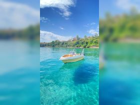 A picturesque view of a boat anchored in crystal-clear waters, surrounded by lush greenery — perfect for a serene day on the water.