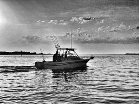 A fishing boat navigates through calm waters at sunset, capturing the essence of a perfect day on the water with friends.