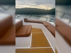Interior view of a spacious boat seating area, featuring comfortable brown cushions and a polished deck, perfect for relaxation while cruising.