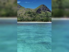 A stunning view of a pristine beach surrounded by lush greenery and clear turquoise waters, perfect for a tropical getaway.