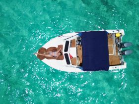 A woman relaxes on a boat in the stunning turquoise waters, perfect for sunbathing and enjoying a day on the water.