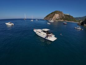 A vibrant scene of guests enjoying a sunny day on the water, with boats anchored near a picturesque island. Perfect for summer adventures and aquatic fun.