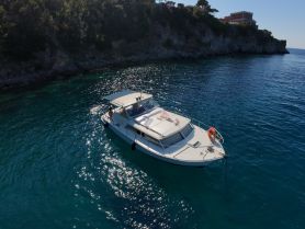 Aerial view of a boat anchored in clear turquoise waters, showcasing its sleek design against a scenic coastal backdrop.